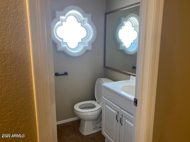 half bath with toilet, tile patterned flooring, and vanity