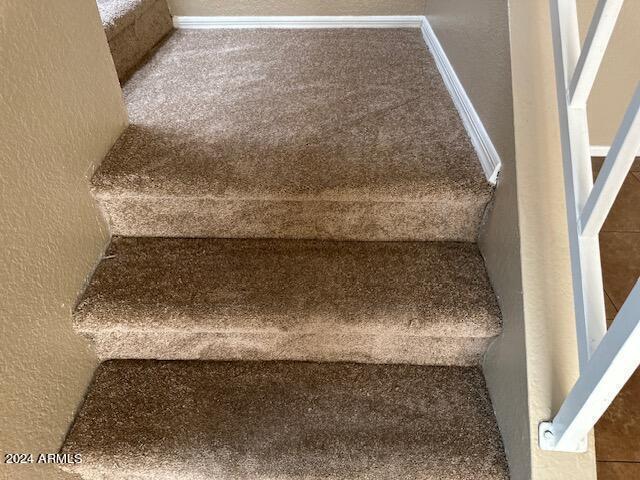 stairs with a textured wall and carpet flooring