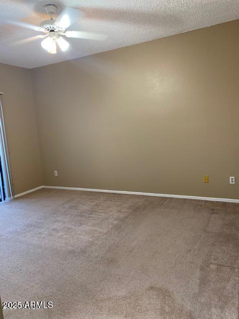 empty room featuring carpet floors, ceiling fan, baseboards, and a textured ceiling