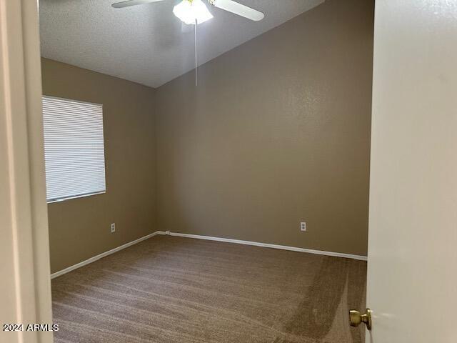 carpeted empty room featuring a ceiling fan, lofted ceiling, a textured ceiling, and baseboards