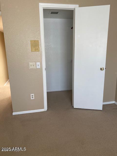 unfurnished bedroom featuring a walk in closet, carpet, a closet, visible vents, and baseboards