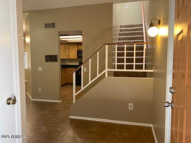 interior space featuring tile patterned flooring, visible vents, and baseboards