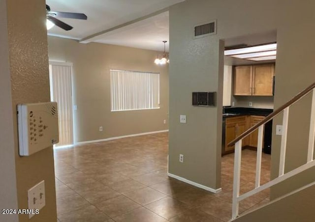 tiled spare room with ceiling fan with notable chandelier, stairway, visible vents, and baseboards