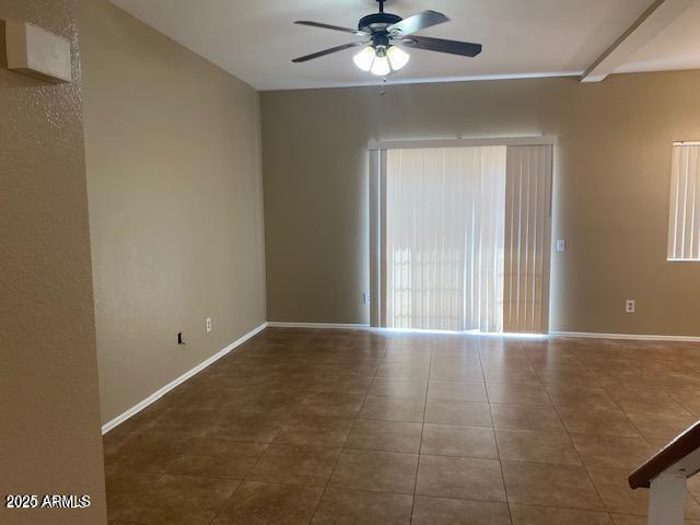 tiled empty room with ceiling fan and baseboards