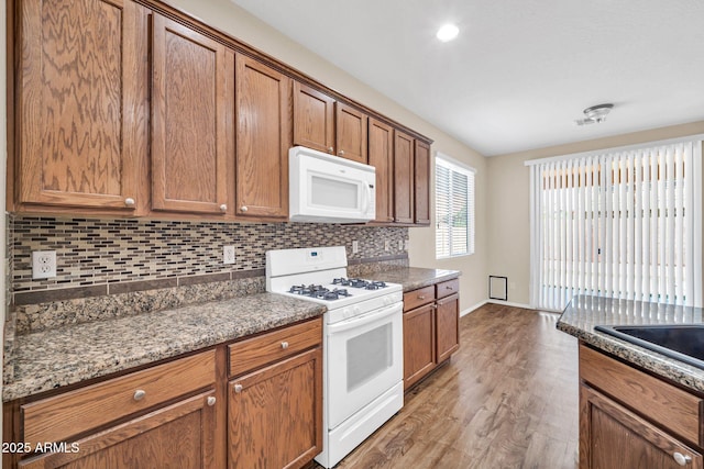 11318 W Monte Vista Rd, Avondale, AZ 85392 - kitchen featuring white appliances, tasteful backsplash, light wood-style floors, brown cabinets, and recessed lighting