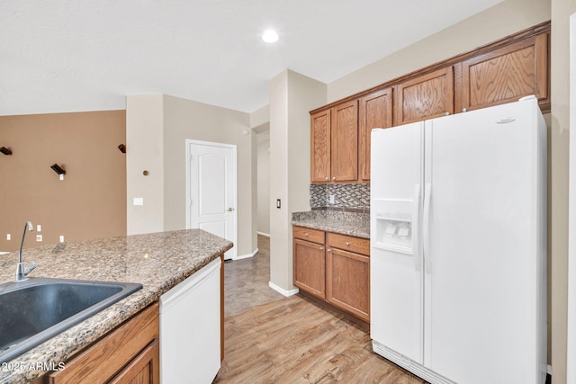 11318 W Monte Vista Rd, Avondale, AZ 85392 - kitchen with white refrigerator with ice dispenser, light wood-style flooring, brown cabinetry, and decorative backsplash