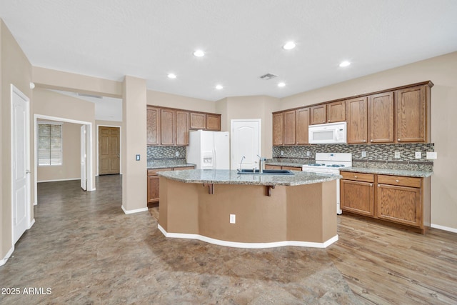 11318 W Monte Vista Rd, Avondale, AZ 85392 - kitchen with white appliances, backsplash, an island with sink, brown cabinets, and recessed lighting