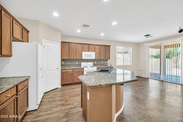 11318 W Monte Vista Rd, Avondale, AZ 85392 - kitchen featuring white appliances, brown cabinetry, an island with sink, backsplash, and recessed lighting