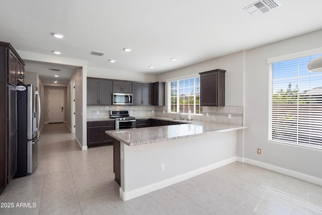 20644 W Mariposa St, Buckeye, AZ 85396 - kitchen featuring stainless steel appliances, a peninsula, decorative backsplash, a sink, and light tile patterned floors