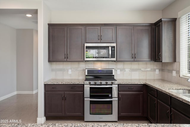 20644 W Mariposa St, Buckeye, AZ 85396 - kitchen featuring stainless steel appliances, dark brown cabinets, decorative backsplash, and baseboards