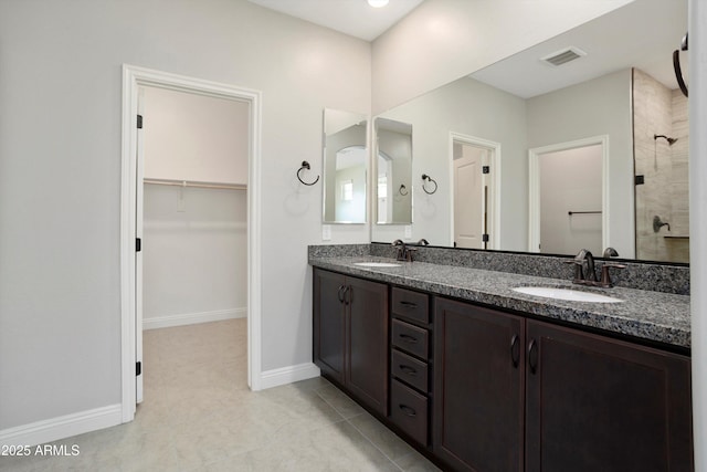 20644 W Mariposa St, Buckeye, AZ 85396 - bathroom featuring a spacious closet, a tile shower, double vanity, baseboards, and tile patterned floors