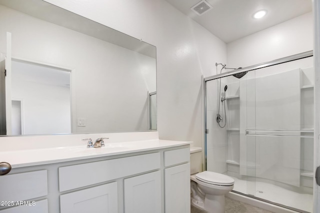 bathroom with vanity, a shower with door, and toilet