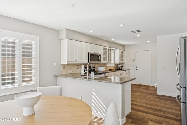 10252 E Butherus Dr, Scottsdale, AZ 85255 - kitchen featuring appliances with stainless steel finishes, dark wood-type flooring, backsplash, glass insert cabinets, and white cabinetry