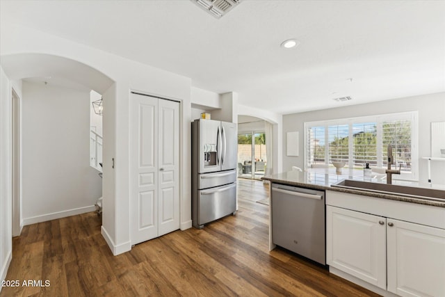 10252 E Butherus Dr, Scottsdale, AZ 85255 - kitchen with appliances with stainless steel finishes, arched walkways, dark wood finished floors, white cabinets, and recessed lighting