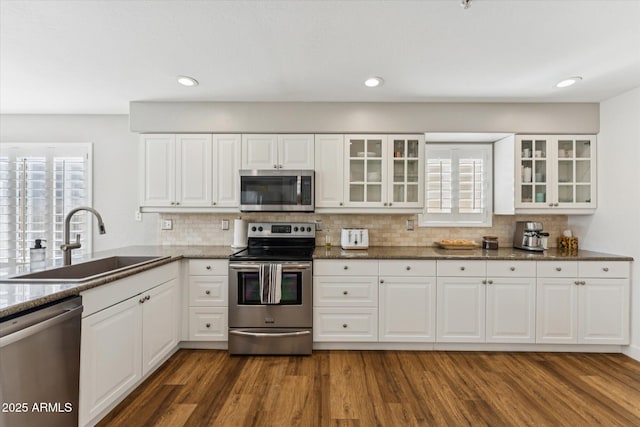 10252 E Butherus Dr, Scottsdale, AZ 85255 - kitchen featuring appliances with stainless steel finishes, dark stone counters, dark wood-style flooring, decorative backsplash, and recessed lighting