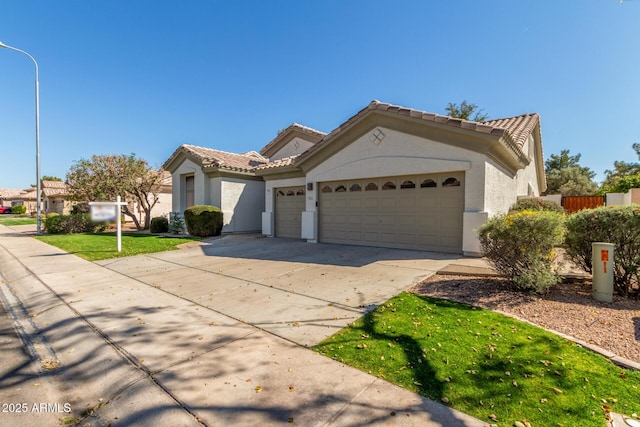 view of front facade featuring driveway, a tiled roof, an attached garage, and stucco siding