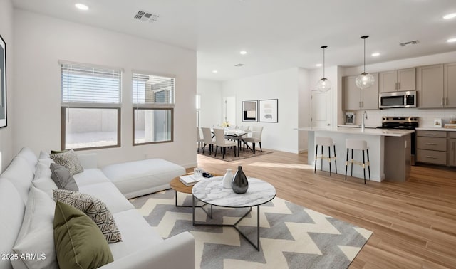 living room featuring light wood finished floors, visible vents, and recessed lighting