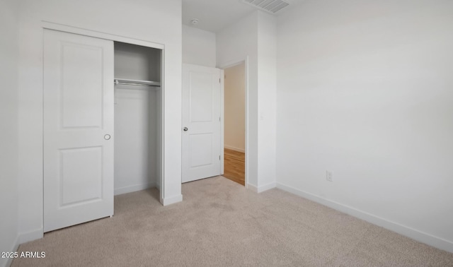 unfurnished bedroom featuring visible vents, baseboards, carpet, and a closet