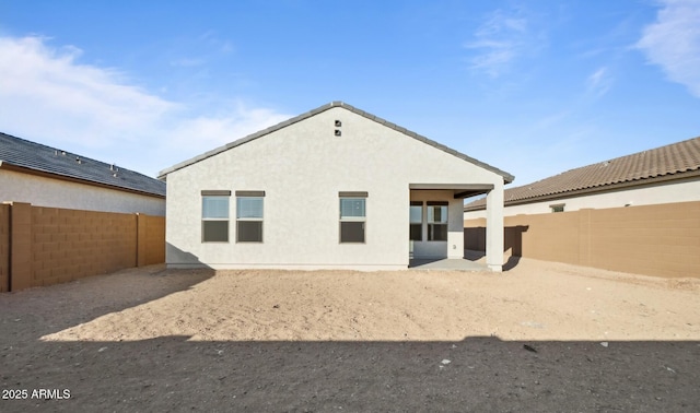 rear view of house with stucco siding, a fenced backyard, and a patio area