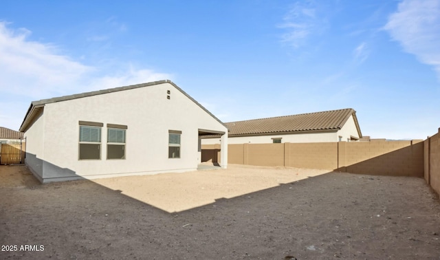 rear view of property featuring stucco siding and a fenced backyard