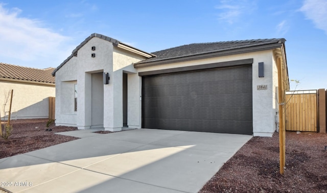 view of front of home featuring stucco siding, driveway, a tile roof, and a garage