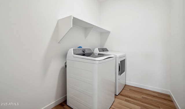 laundry room with laundry area, washer and dryer, light wood-style floors, and baseboards