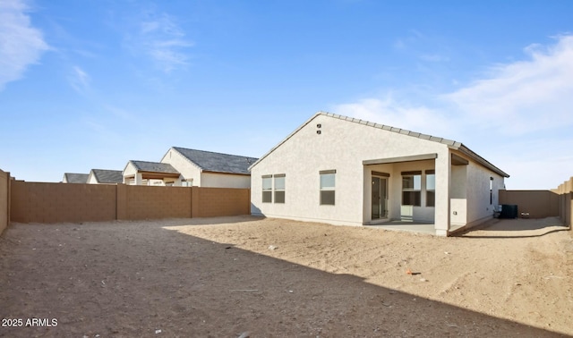 rear view of property featuring stucco siding, cooling unit, a fenced backyard, and a patio area