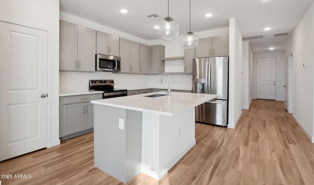 kitchen featuring visible vents, gray cabinets, stainless steel appliances, and a sink