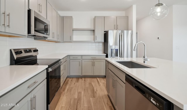 kitchen featuring open shelves, stainless steel appliances, gray cabinetry, and a sink