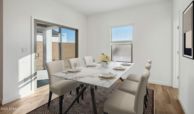 dining area with baseboards, plenty of natural light, and light wood-style floors