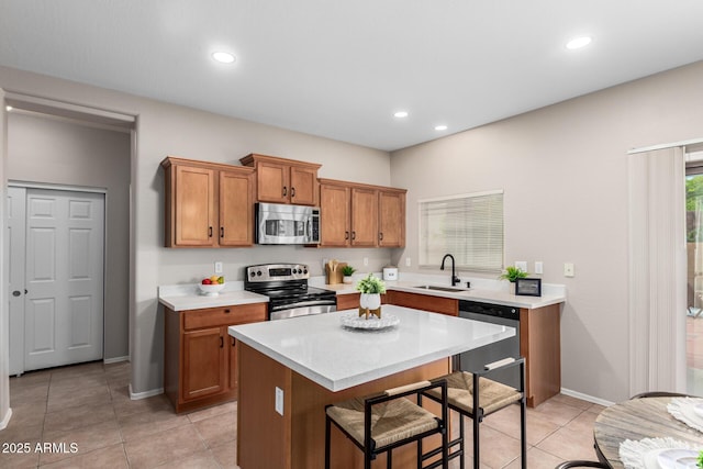 kitchen with a breakfast bar, stainless steel appliances, sink, a kitchen island, and light tile patterned flooring