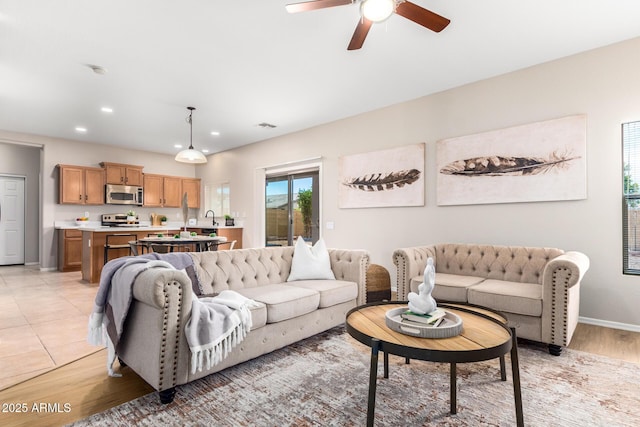 tiled living room with ceiling fan and sink