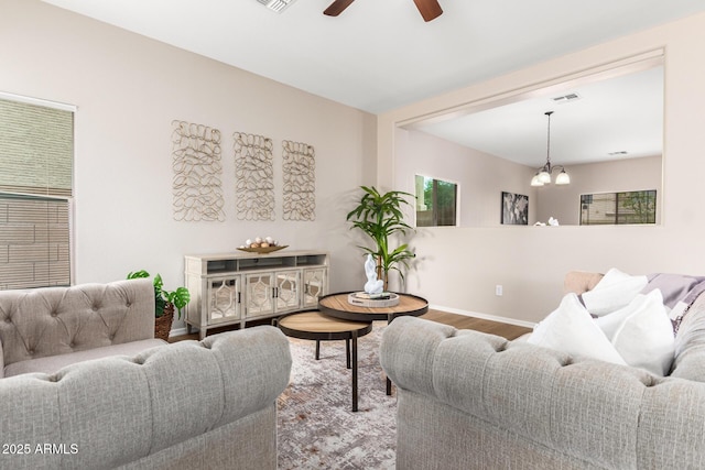 living room with ceiling fan with notable chandelier and wood-type flooring