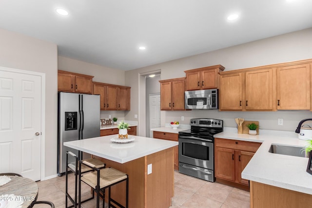 kitchen with a breakfast bar, a center island, sink, light tile patterned floors, and stainless steel appliances