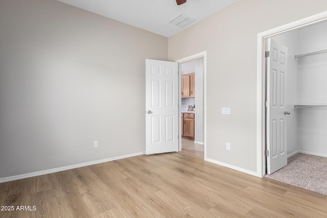 unfurnished bedroom with ceiling fan, a closet, and light wood-type flooring