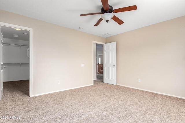 unfurnished bedroom featuring carpet flooring, ceiling fan, a spacious closet, and a closet