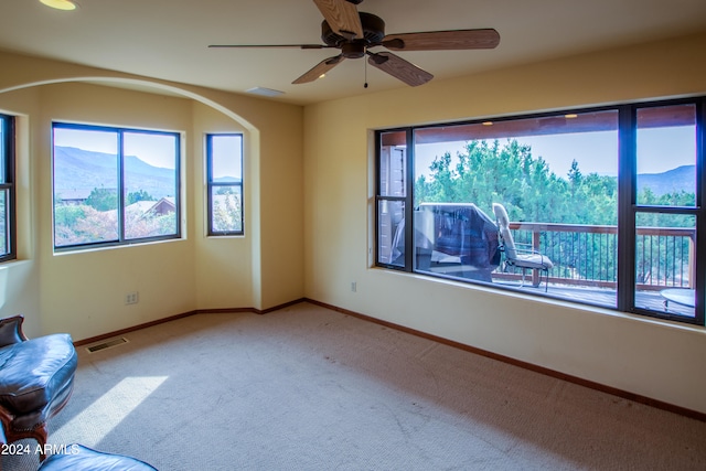 carpeted spare room featuring a mountain view and ceiling fan