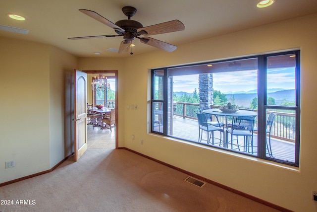 empty room featuring ceiling fan, light colored carpet, and a mountain view