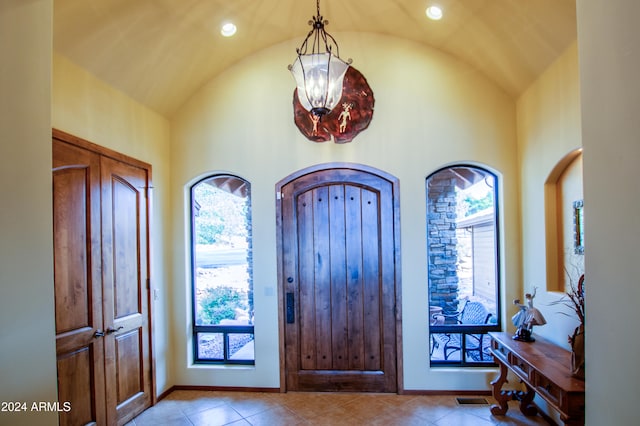 tiled foyer entrance with a chandelier, a wealth of natural light, and lofted ceiling