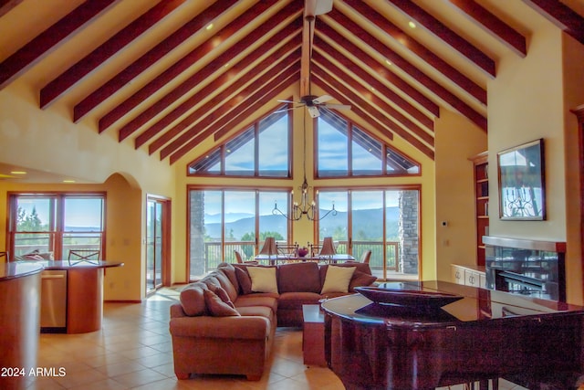 tiled living room featuring beamed ceiling, a mountain view, ceiling fan with notable chandelier, and high vaulted ceiling