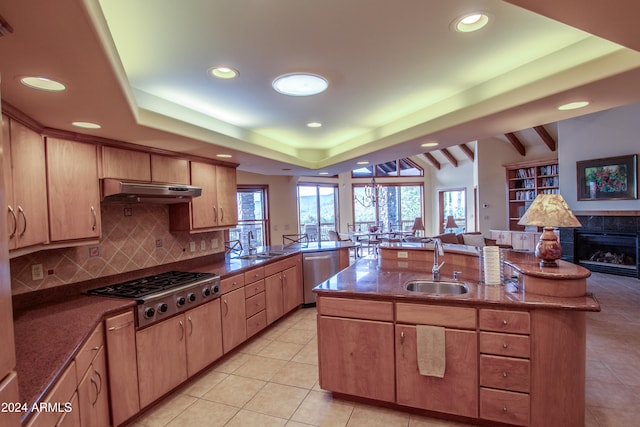 kitchen with light brown cabinets, sink, light tile patterned floors, a fireplace, and appliances with stainless steel finishes