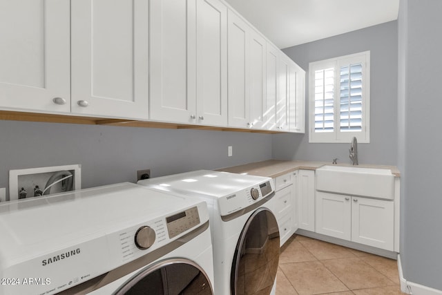 washroom with washing machine and dryer, cabinets, light tile patterned flooring, and sink