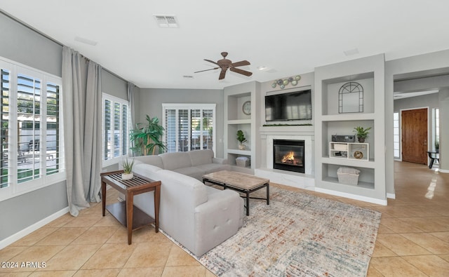 living room with built in shelves, a wealth of natural light, and light tile patterned flooring