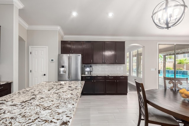 kitchen featuring crown molding, a notable chandelier, arched walkways, decorative backsplash, and high quality fridge