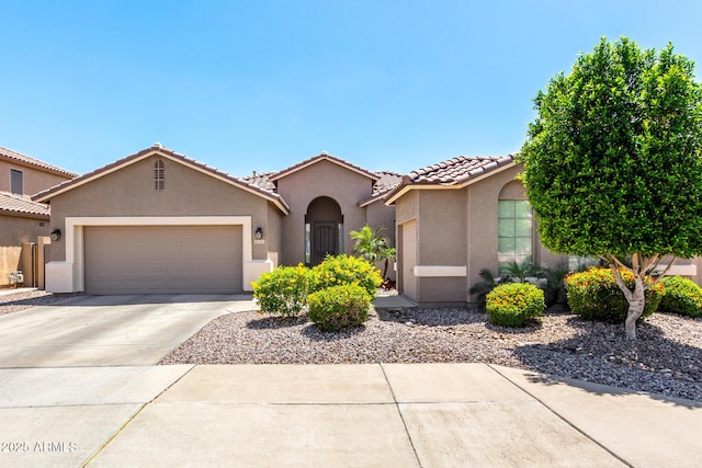 mediterranean / spanish house with concrete driveway, a garage, a tile roof, and stucco siding