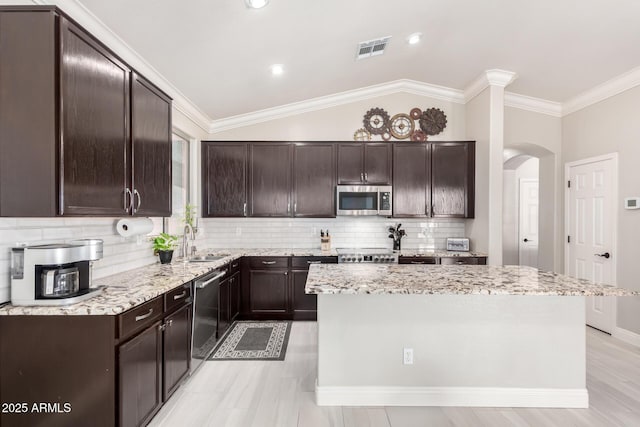 kitchen featuring dark brown cabinetry, appliances with stainless steel finishes, arched walkways, a center island, and visible vents