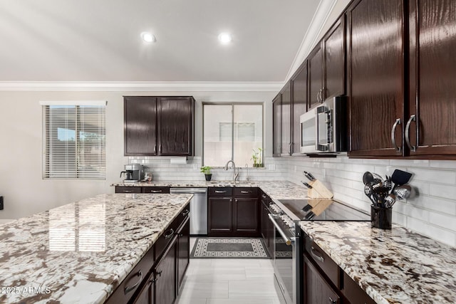 kitchen featuring backsplash, appliances with stainless steel finishes, a sink, light stone counters, and ornamental molding