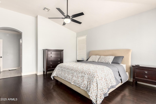 bedroom with visible vents, wood finished floors, baseboards, arched walkways, and vaulted ceiling