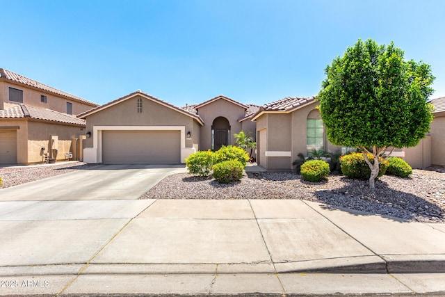 mediterranean / spanish-style home with a garage, stucco siding, concrete driveway, and a tile roof