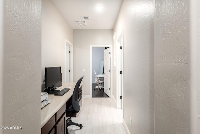 office with visible vents, baseboards, and a textured wall